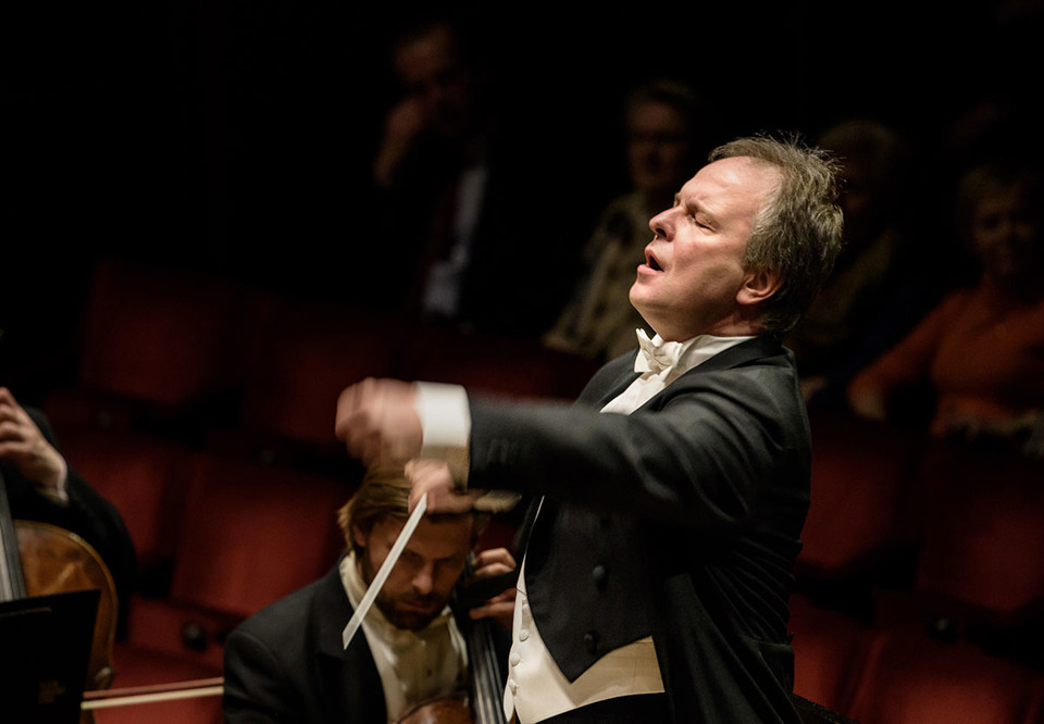 Man som dirigerar stor orkester. Fotografi.