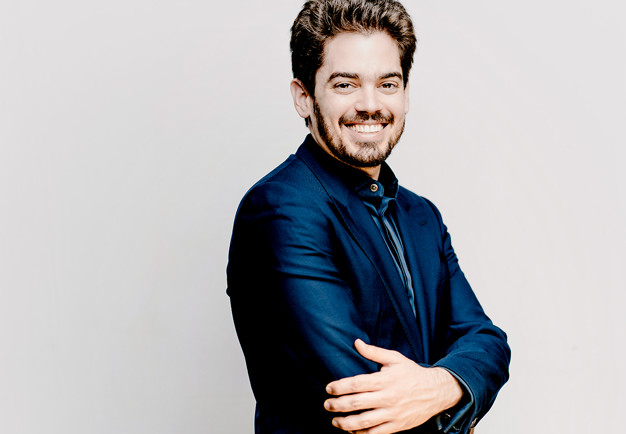 Young conductor with drk hair smiling on stage