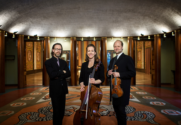 Three muscians standing in the Grünewald foyer with their instruments. Photo.