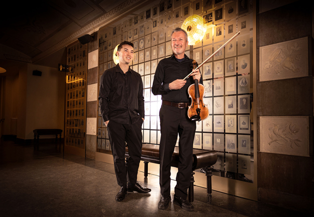 Two musicians standing up. Photo.