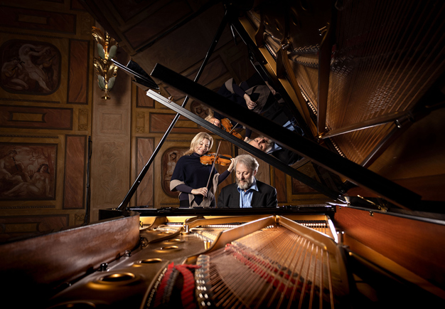 En kvinna spelar fiol och en man spelar piano. Fotografi.