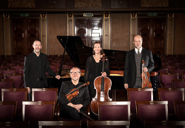 Four musicians amoong chairs in Grünewaldsalen. Photo.