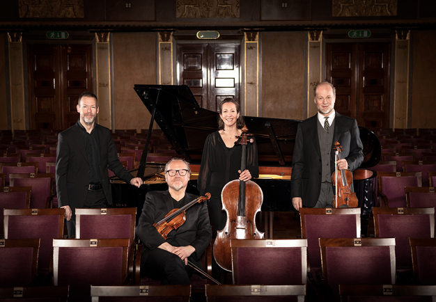 Four musicians amoong chairs in Grünewaldsalen. Photo.