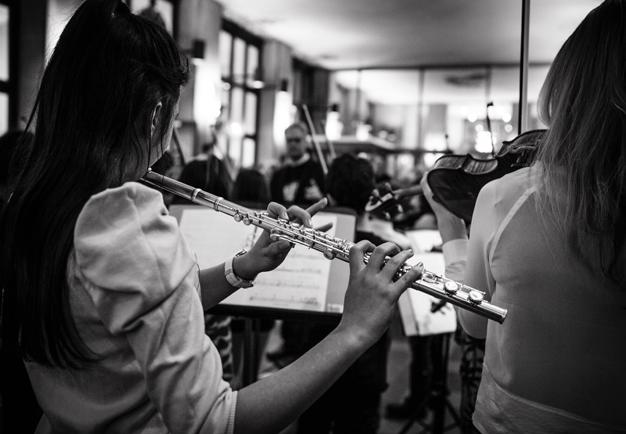 Black and white photo of a child playing the flute. Picture taken from behind. 