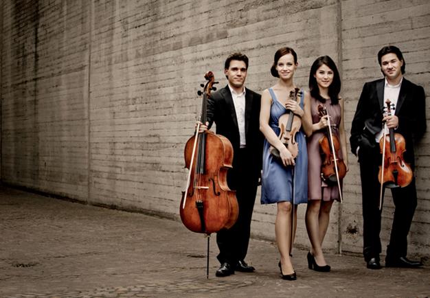 Four musicians standing with their instruments. Photo