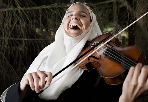 A laughing nun playing violin. Photo.
