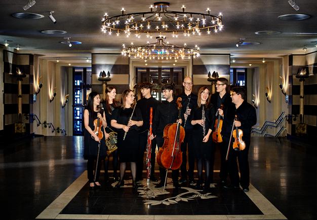 Bild på ensemblen. Glad stämning, de håller i sina instrument. KOnsertklädda. Fotog