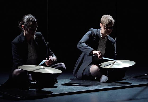 Two women sitting on the floor playing on cymbals.