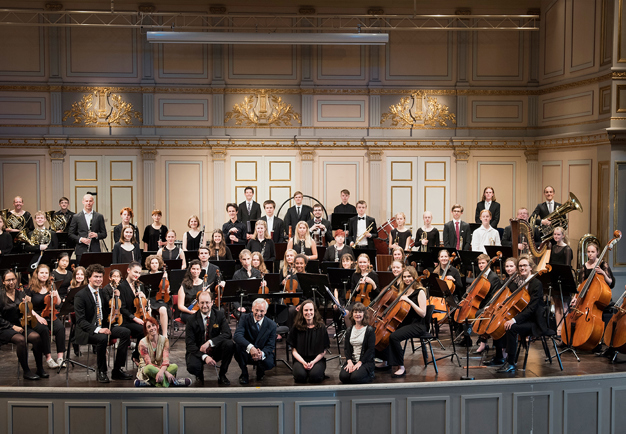 Stor orkester med ungdomar. Fotografi.