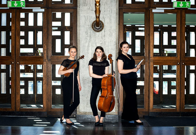 Tre kvinnor ståendes med sina instrument i Konserthusets vestibul. Fotografi.