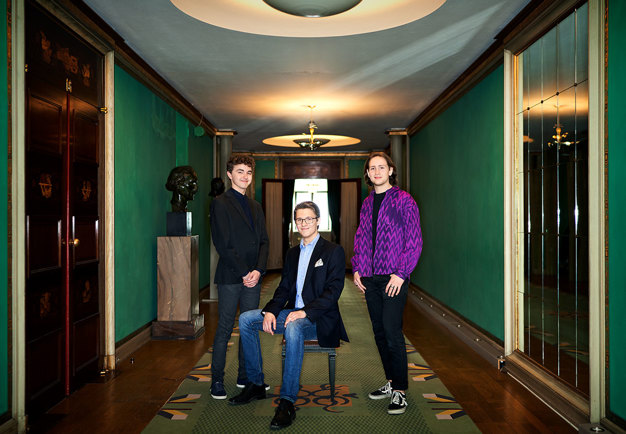 Three guys standing in a green corridor. Photo.