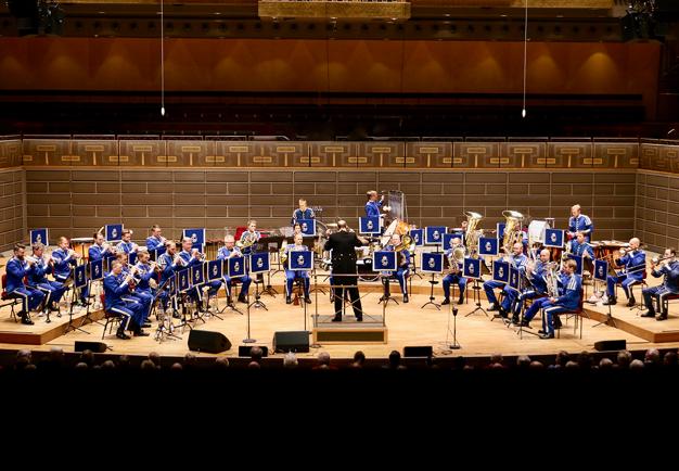 Män i militäruniform som spelar instruemnt i Stoa Salen Konserthuset. Fotografi.