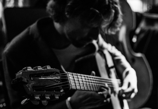 Man som spelar gitarr. Fotografi.