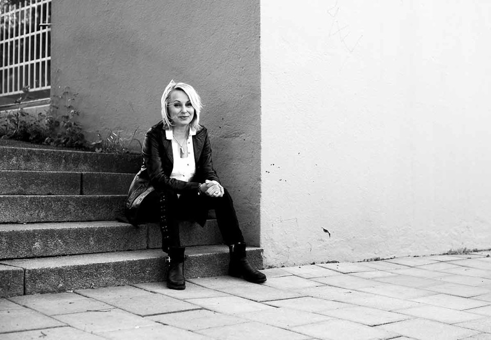 Svartvit bild på Louise som sitter i en trappa. Ser glad ut. Fotografi.