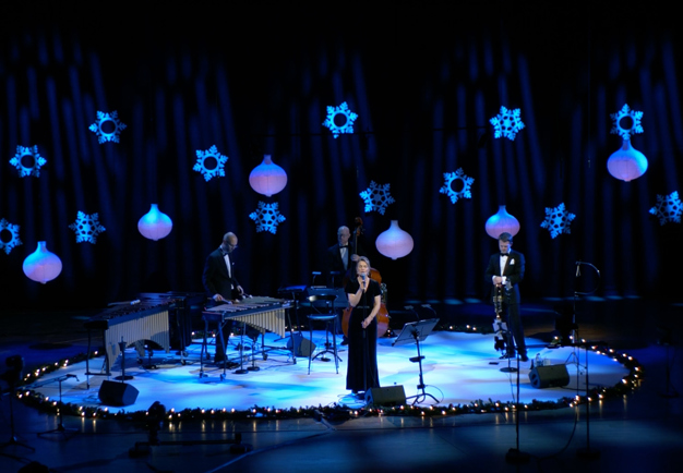 Fyra musiker på scen i blått ljus. Fotografi.