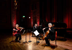 En pianist, en cellist och en violinist. Fotografi.