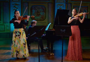 Two violinists and one man playing the piano. From the concert.