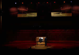 Man standing in front of an organ. Photo.