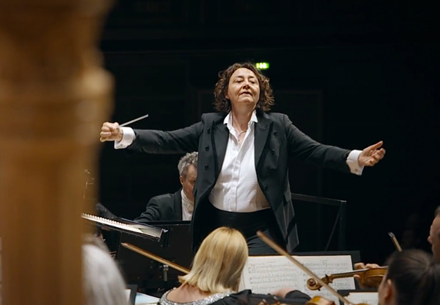 Female conductor conducting large orchestra. Photo.