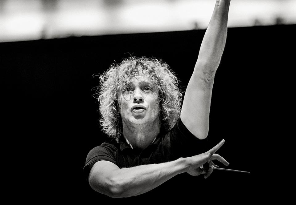 Man with curly hair conducting.