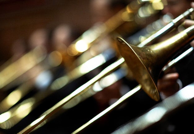 Ett antal tromboner med blank mässing. Fotografi.