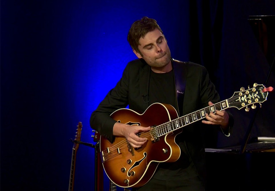 Man som håller i gitarr. Fotografi