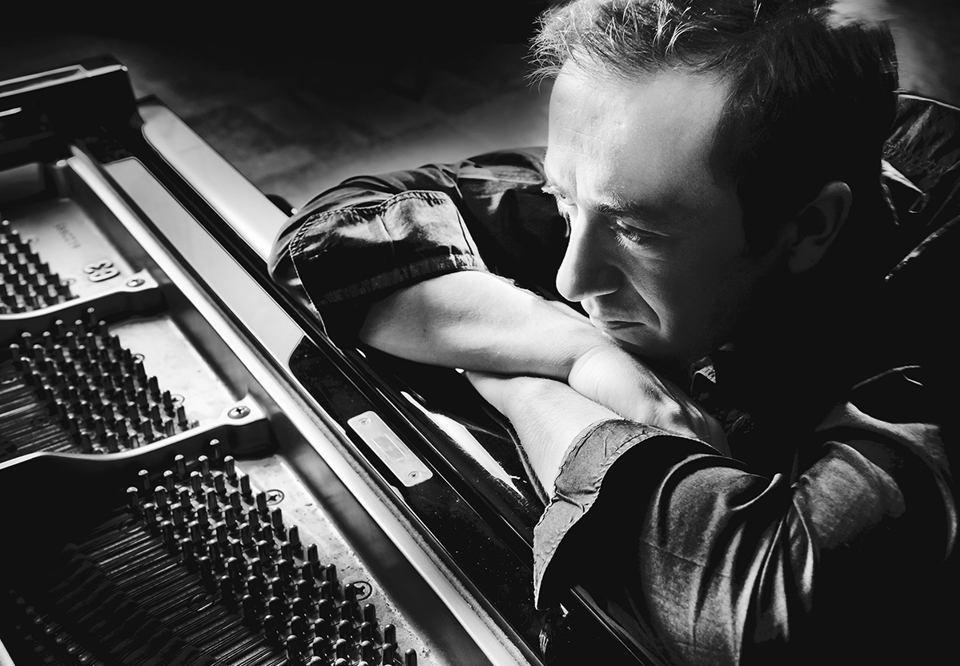 Man who is leaning against a piano. Photo. Fotografi.