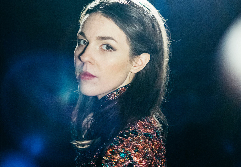 Närbild på kvinna mot blå bakgrund. Fotografi.