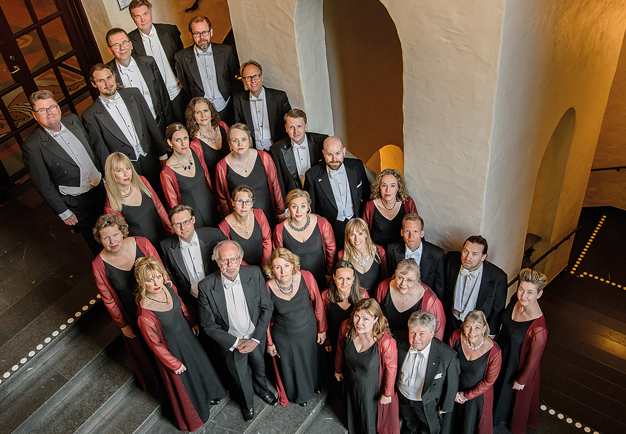 Gruppbild tagen ovanfrån. Ett tjugotal personer står uppklädda och ser in i kameran.