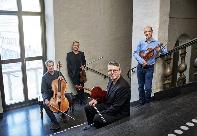 Bild på fyra musiker som står och sitter i trappan in till Grünewaldsalen, Fotografi.