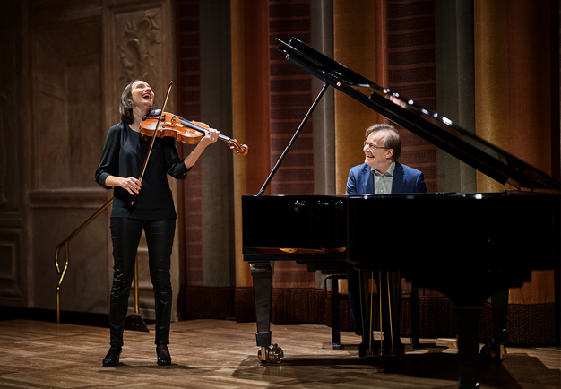 A happy girl playing the violin and a happy man playing the piano. Photography.