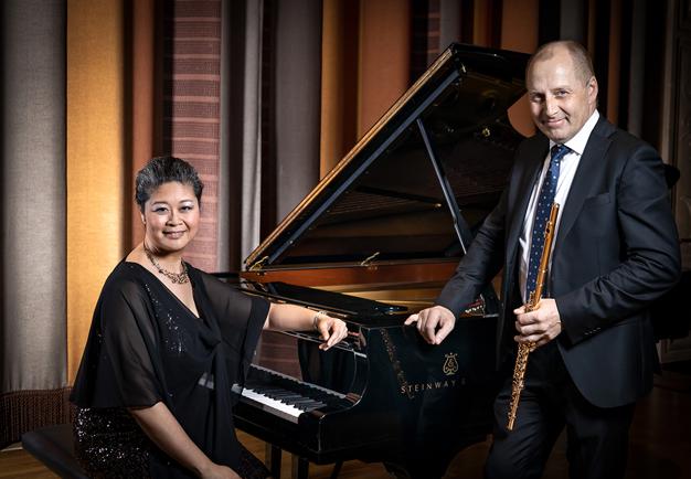 Musicians standing by the piano. Photo.