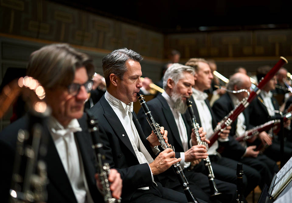 Foto över orkesterns träblåssektion i konsertkläder.