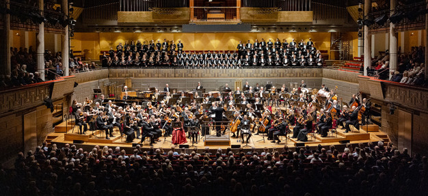 Gruppbild på Kungliga Filharmonikerna inne på podiet i Stora salen. Fotografi.