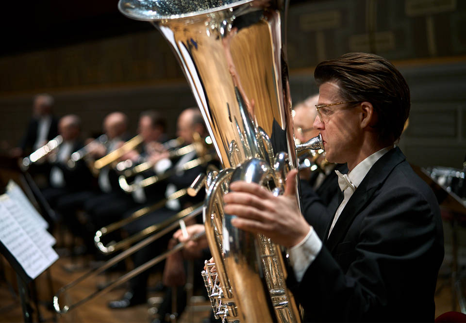 Man som spelar tuba, i bakgrunden de andra blåsarna