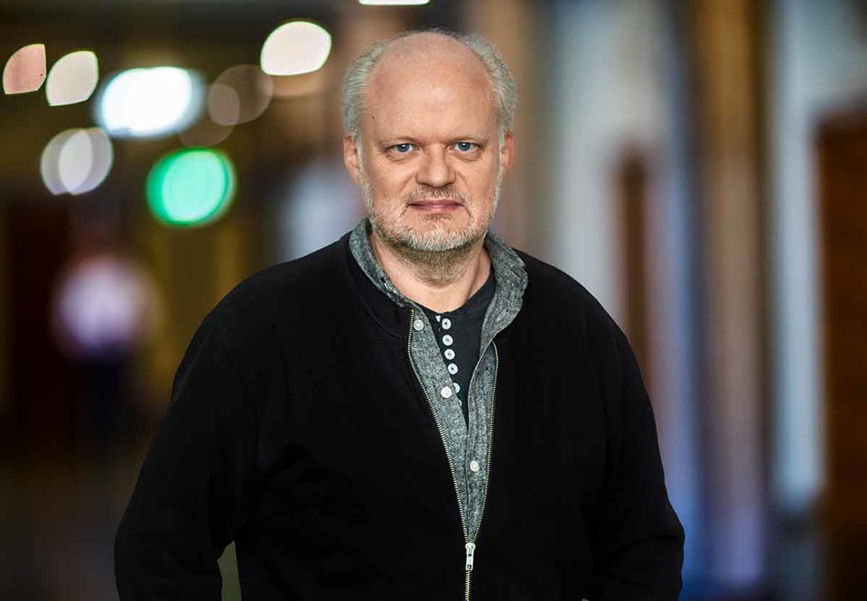 Jens-Christoph ler och ser glad ut. Porträttbild. Fotografi.