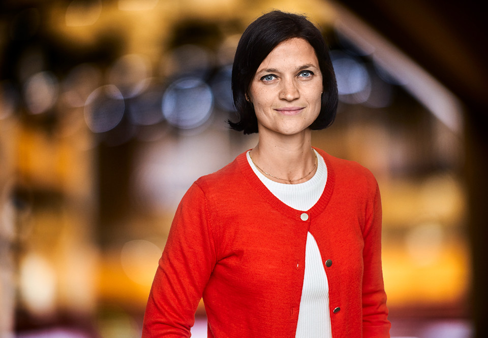 Smilande filharmoniker med vit tröja samt orange kofta. Nadine Jurdzinski. Fotografi.