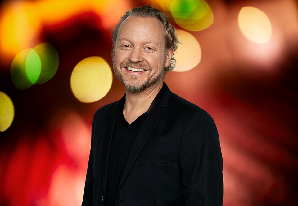 Leende man mot röd diffus bakgrund. Fotografi.