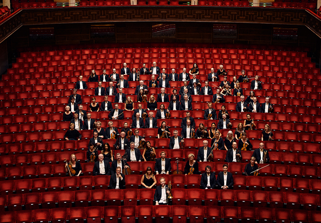 Hela Kungliga Filharmonikerna sitetr i stolarna i Stora salen. Fotografi.