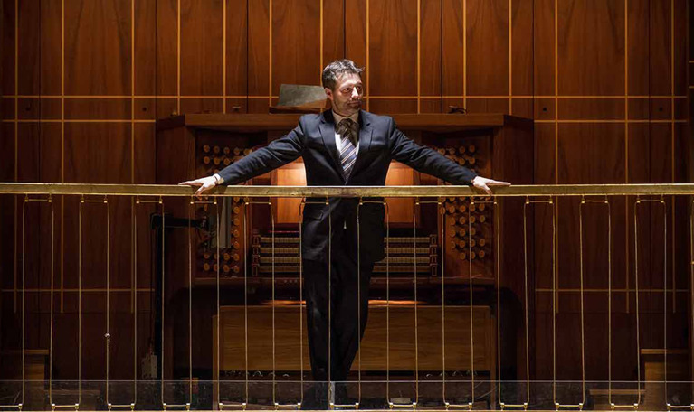  Man standing in front of the organ´s keyboard. Photo.