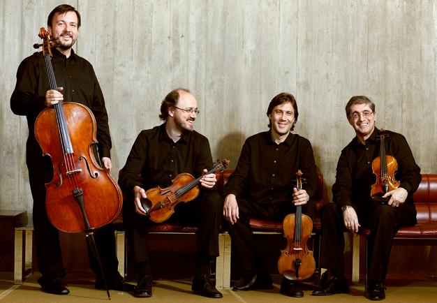 Medlemmarna i kvartetten står tillsammans på en gruppbild. Håller sina instrument. Fotografi.