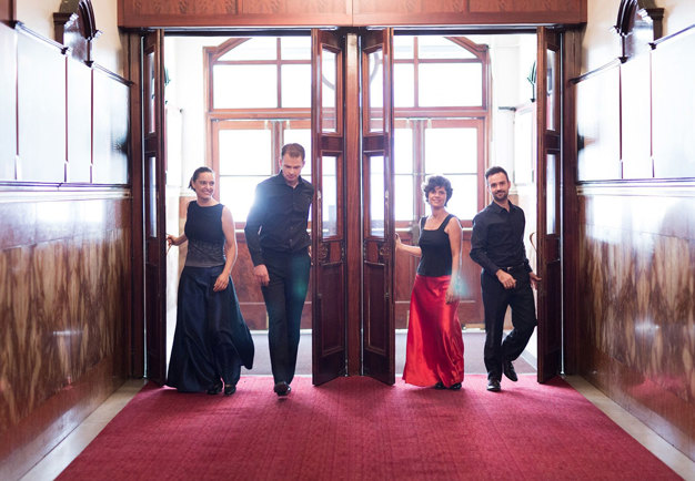 Group picture. The quartet is walking in a hotel lobby. Photography.