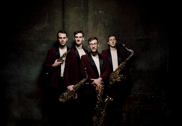 Fyra unga män med sina saxofoner. Fotografi.