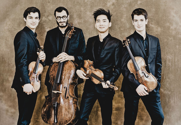 Four young men leaning against a brown background. Photo.