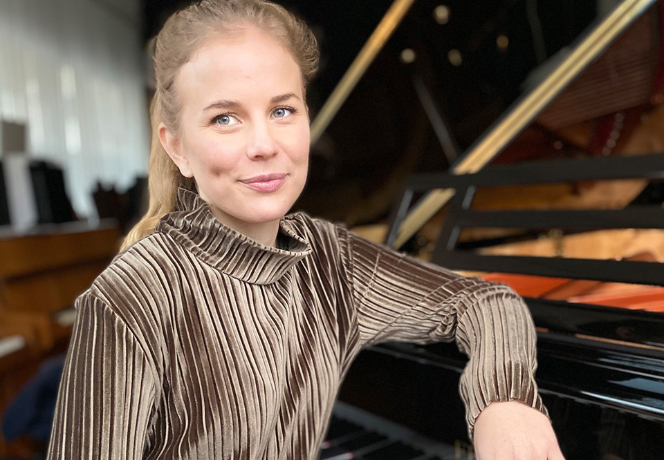 Woman sitting by a piano. Photo.