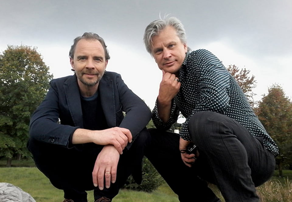 Two men sitting and looking into the camera