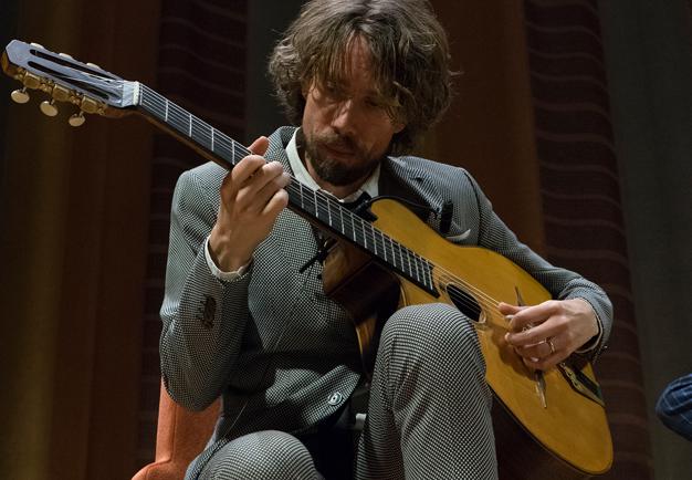 Man som spelar gitarr. Fotografi.