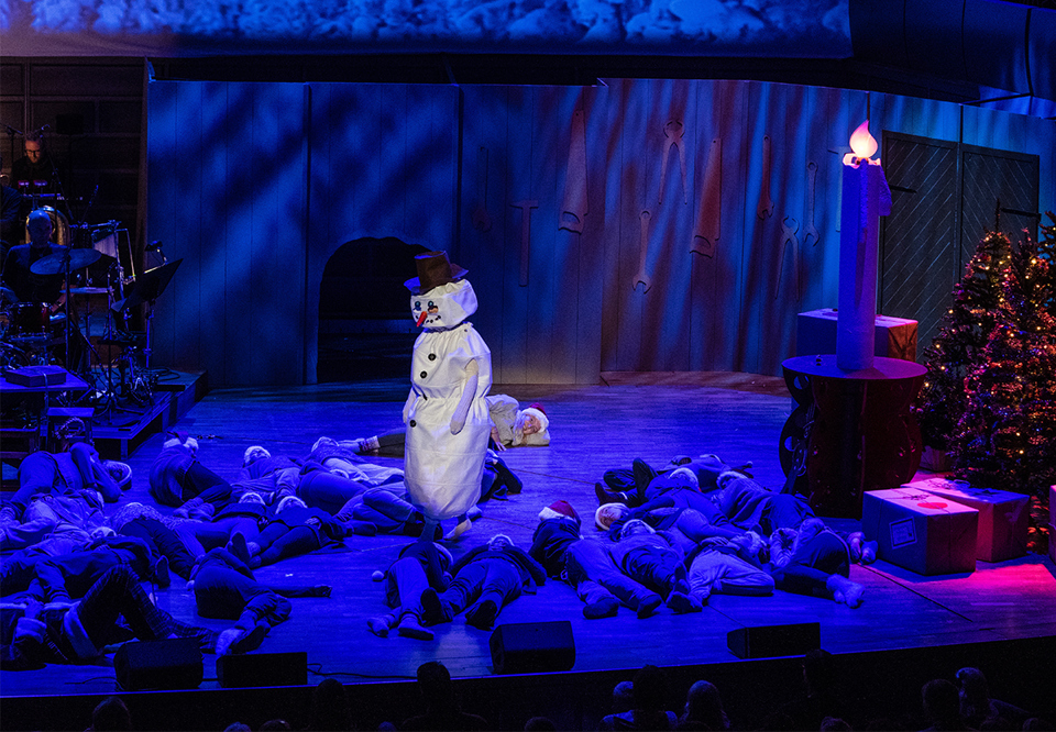 Snögubbe på Stora scenen i blå ljussättning. Fotografi.