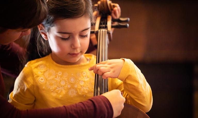 Children tries to play cello. Photo.