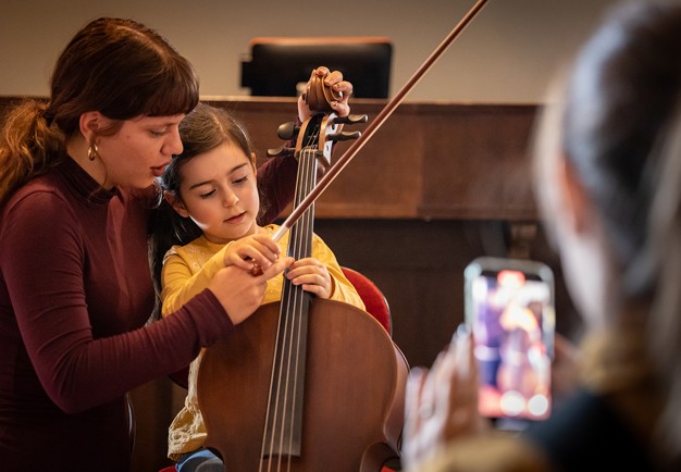 Children tries to play cello. Photo.